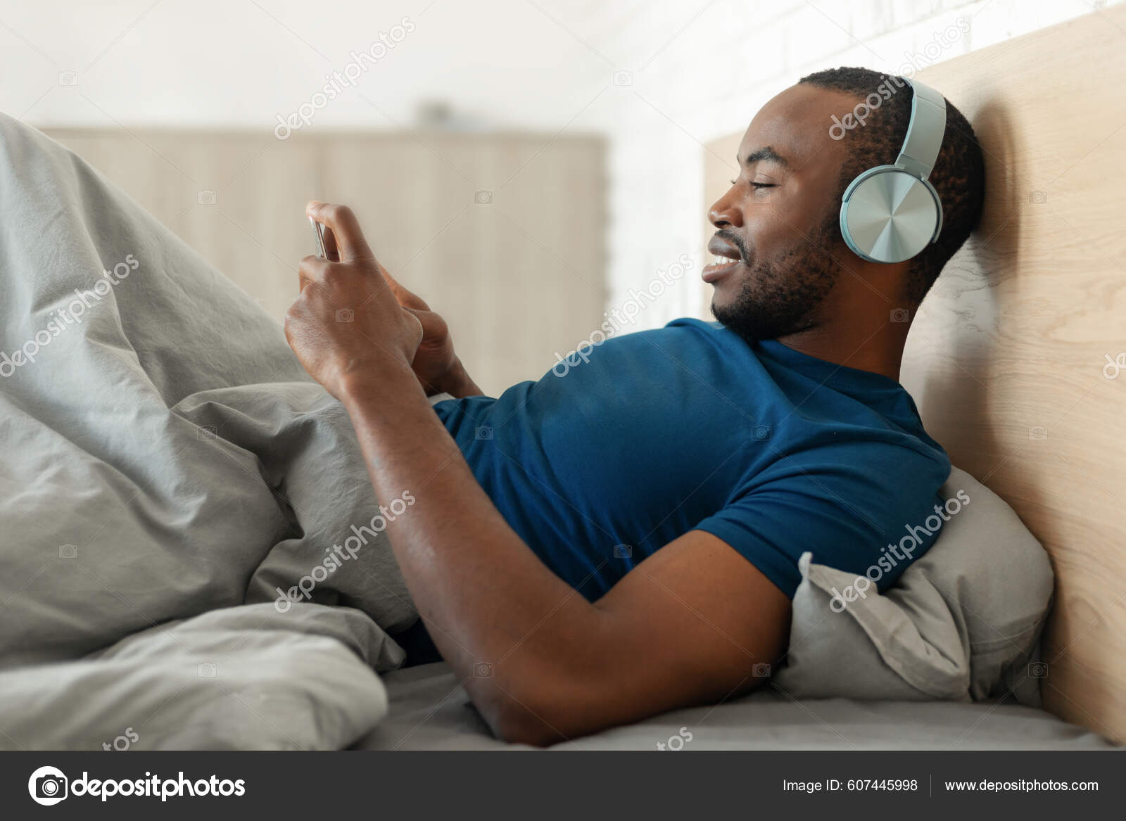 Happy Afrifcan American Man Using Mobile Phone Wearing Headphones