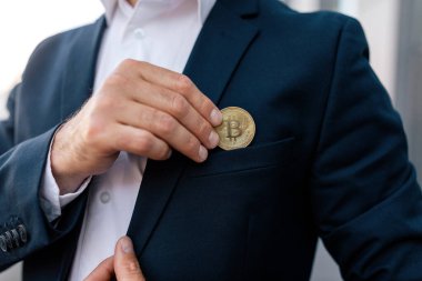 Kendine güveni tam, beyaz takım elbiseli CEO 'su bitcoin' i modern açık havanın yakınına koyuyor, kapıyor, kırpıyor. Başarılı bir iş, iş adamı kripto para, kar ve kazanç öneriyor