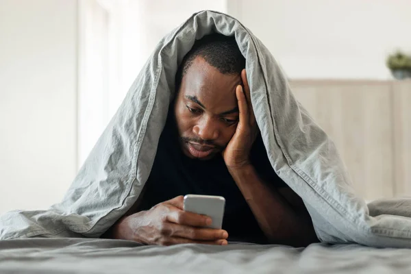 Ύπνος Μαύρος Τύπος Χρησιμοποιώντας Smartphone Που Βρίσκεται Στο Κρεβάτι Καλυμμένο — Φωτογραφία Αρχείου