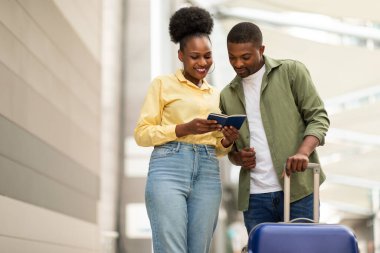 Neşeli Afro-Amerikan turistler birlikte seyahat ediyorlar. Pasaportlarını tutuyorlar. Bavulları açık havada duruyor. Tatil Seyahat Konsepti