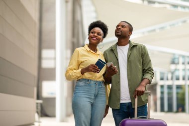 Neşeli Siyah Turistler Cep Telefonu Rezervasyon Biletlerini Çevrimiçi Cep Telefonu Başvurusu ile Açık Havalimanı Terminali 'nin yanında duran Gezgin Çiftler. Teknoloji ve Turizm Konsepti