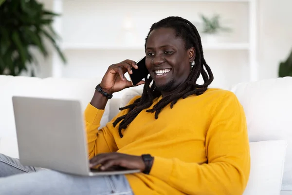 Feliz Joven Afroamericano Hombre Usando Ordenador Portátil Hablando Teléfono Móvil —  Fotos de Stock