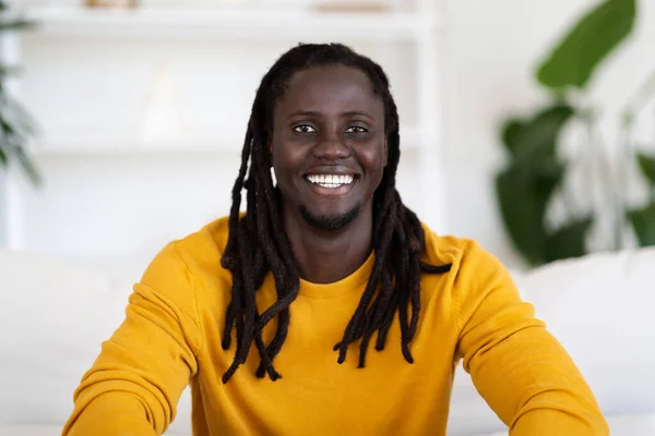 Portrait Of Smiling Young Black Male Posing In Home Interior, Millennial African American Man With Dreadlocks Sitting On Couch In Living Room And Smiling At Camera, Closeup Shot With Free Space