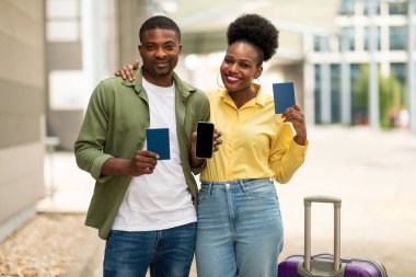 Mutlu Afrikalı Amerikalı Turistler Akıllı Telefon Boş Ekran Gösteren Pasaportlu Seyahat Biletleri Çevrimiçi Havalimanı 'ndaki Bavul Poz Veren Kameraya Gülümsüyor. Model