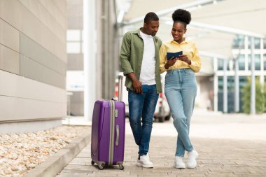 Turizm. Afro-Amerikan Turistler Pasaportlu Çiftler, Bavullarıyla Açık Hava Alanı 'nın yanında duruyorlar. Milenyum Eşleri Birlikte Seyahat Ediyor. Tatil Seyahat Konsepti. Tam Uzunluk Çekimi