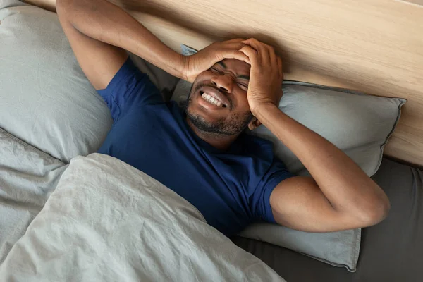 非洲裔美国人头痛医患躺在床上 头痛医患 睡眠不足 躺在现代卧房室内 健康问题 以上视图拍摄 — 图库照片