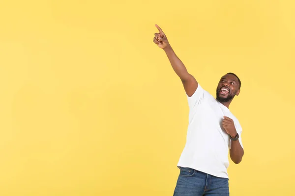 興奮アフリカ系アメリカ人の男は テキスト広告のための空のスペースの近くにポーズを指を指す偉大なオファーは黄色の背景の上に立って スタジオショット — ストック写真