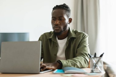 Laptop bilgisayarında çalışan ciddi bir çalışanın portresi, ofis masasında oturan, klavyede yazan ve bilgisayar ekranına bakan erkek girişimci, boşluğu kopyalayan