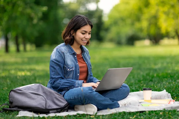 距離学習 公園で遊んでいる間 ラップトップの屋外での若い中東女性学生の研究 コンピュータを使用して幸せな千年紀のアラブ人女性 オンライン学習を楽しんで スペースをコピー — ストック写真
