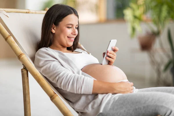 Sonriendo Embarazada Navegando Por Internet Teléfono Inteligente Mientras Relaja Silla — Foto de Stock