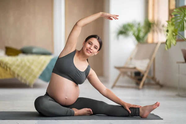 自宅で出生前体操を行う美しい妊婦の笑顔の肖像 リビングルームでフィットネスマットでアクティブウェアトレーニングで若い期待女性 ストレッチ側面 スペースをコピー — ストック写真