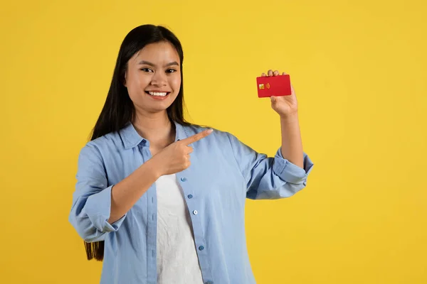 クレジットカードでのカジュアルなショーの指で笑顔千年の中国の女性の学生は 黄色の背景 スタジオに隔離されたオンラインショッピングをお勧めします 広告やオファー 販売やショッピングを楽しむ購入 — ストック写真
