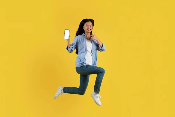 Neşeli Genç Japon Kız Öğrenci Gündelik Atlama Yapıyor Akıllı Telefonu — Stok fotoğraf