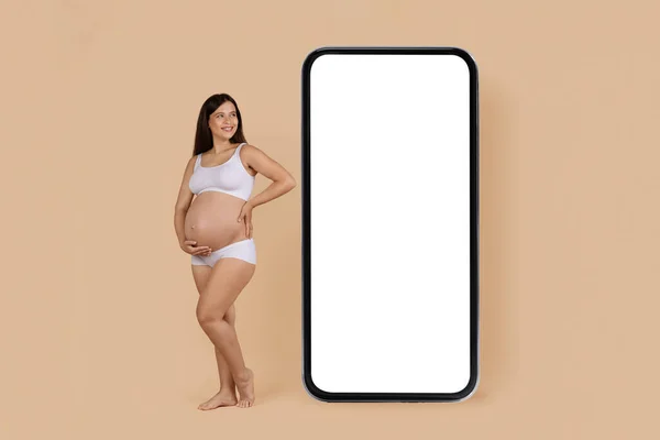 Aplikasi Seluler Happy Pregnant Woman Underwear Standing Huge Blank Smartphone — Stok Foto