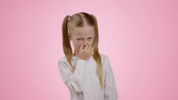 気の利いた匂い かわいい女の子臭い何か恐ろしい 彼女の鼻とぎらぎらと 眉をひそめる顔 ピンクのスタジオの背景 スローモーション — ストック動画