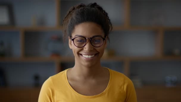 快乐的生活身着眼镜的无忧无虑的非洲裔美国女士的近照 对着镜头微笑 在家里摆姿势 动作缓慢 — 图库视频影像