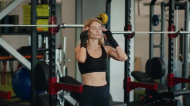 Sportif yaşam tarzı konsepti. Spor takım elbiseli mutlu orta yaşlı kadın sporcunun kapalı çekimleri, modern spor salonunda antrenman yapmanın keyfi, yavaş çekim, serbest alan