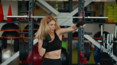Savunma eğitimi. Spor salonunda orta yaşlı aktif bir kadın boks yapıyor. Bando yumruklarına sarılmış havayı yumrukluyor. Yavaş çekim, serbest alan.