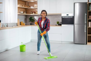 Lastik eldivenli mutlu siyahi kadın minimalist mutfak içi paspasla yerleri yıkıyor, tam boy, kopyalama alanı. Ev işleri, temizlik ve hijyen, sadece sağlık ve ev temizliği.