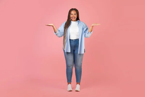 Glückliche Übergewichtige Afroamerikanerin Mit Unsichtbaren Objekten Auf Händen Posiert Lächelnd — Stockfoto