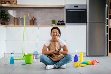 Genç siyahi bayanın paspasla yerde oturmasına ve beyaz mutfak içinde meditasyon yapmasına sevindim. Huzur ve sükunet, ev işleri, temizlik ve hijyen, evde tek başına sağlık hizmetleri