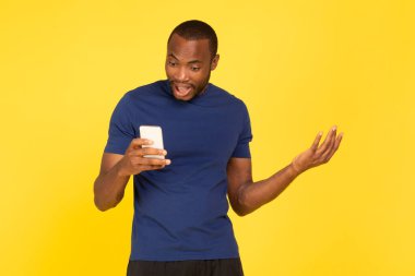 Hoşnutsuz siyah atlet elinde telefonla Negatif Mesaj okuyor ve cep telefonuyla Sarı Stüdyo 'nun arkasında duruyor. Kötü Mobil Uygulama Konsepti