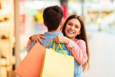Mutlu Eş Kucaklaşan Koca Hafta Sonu Alışveriş Merkezi 'nde Birlikte Alışverişin keyfini çıkarıyor. Eşler Hipermarkette Alışveriş Torbaları Kucaklıyor. Büyük Satış Teklif Konsepti. Seçici Odaklanma