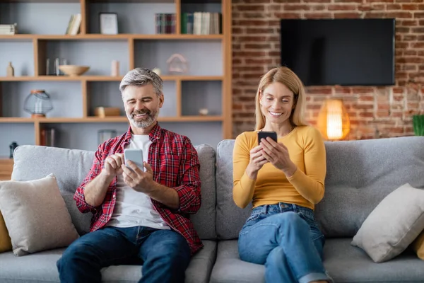Šťastné Dospělé Evropské Rodiny Chatování Chytrých Telefonech Sedět Pohovce Útulném — Stock fotografie