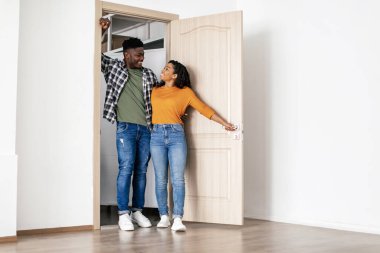 Aile Konutları. Neşeli Afro-Amerikan eşleri, Neşeyle Kucaklaşan Yeni Ev Taşınma Apartmanlarının Kapılarında Duruyorlar. Harika bir emlak teklifi. Tam Uzunluk Çekimi