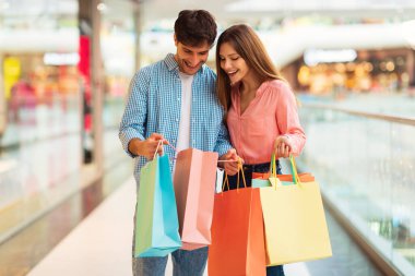 Modern hipermarkette hafta sonları alışveriş torbalarını araştıran mutlu alıcılar çifti. Eşler yeni kıyafetler alıyor. Büyük Satışlar Reklam Konsepti