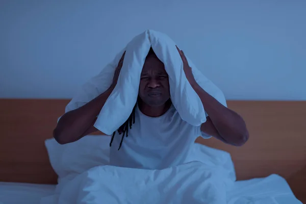 Uykusuzluk Konsepti Geceleri Yatakta Yatarken Yastıkla Kulaklarını Kapatan Siyah Adam — Stok fotoğraf