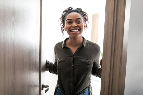 Cheerful Black Female Opening Door Standing Smiling To Camera At Home. Woman Welcoming And Meeting You In New Apartment. Great Real Estate Offer Concept