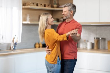 Güzel, olgun eşler mutfakta birlikte dans ediyor, mutlu, orta yaşlı yakışıklı adam evde güzel sarışın karısıyla romantik bir akşam geçiriyor, fotokopi çekiyor. İlişki, evlilik, aile.