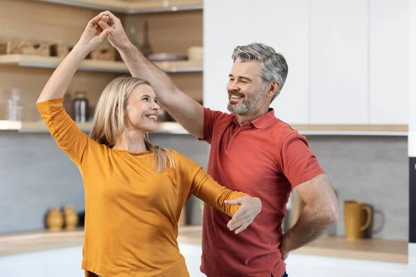 可爱的中年夫妇穿着休闲装在厨房边跳舞边做饭 面带微笑 快乐的丈夫与他美丽的妻子共度时光 复制空间 — 图库照片