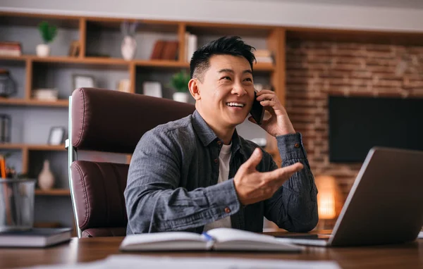 Усміхнений Красивий Дорослий Китайський Чоловік Столом Ноутбуком Говорить Телефону Клієнтом — стокове фото