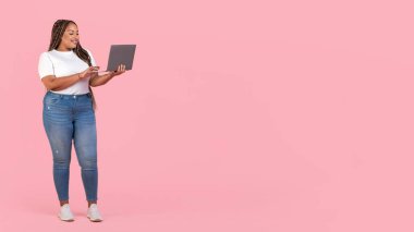 Afro-Amerikan Kadın Serbest Çalışan İnternette Laptop Tarama ve Çevrimiçi Reklam Sitesi Pembe Stüdyo Arkaplanda Duruyor. Metin için Boş Alanı Olan Panorama