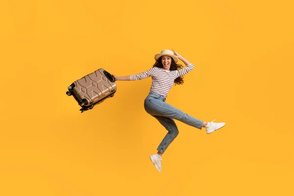 Veselý Mladý Žena Cestující Skákání Kufrem Rukou Přes Žluté Pozadí — Stock fotografie