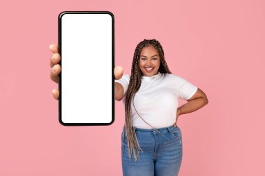 Siyah Artı Boyutlu Kadın Pembe Stüdyo Arkaplanında Gülümseyen Gülümseyen Kamera 'ya Büyük Cep Telefonu Boş Ekran Gösteriyor. Bu Uygulamayı Kontrol Et. Gadgets Teklif Konsepti. Model