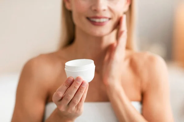皮肤护理的概念 无法辨认的中年妇女拿着装有润肤霜的罐子 在脸上涂上滋养乳液 有选择性地集中注意 进行修剪 — 图库照片