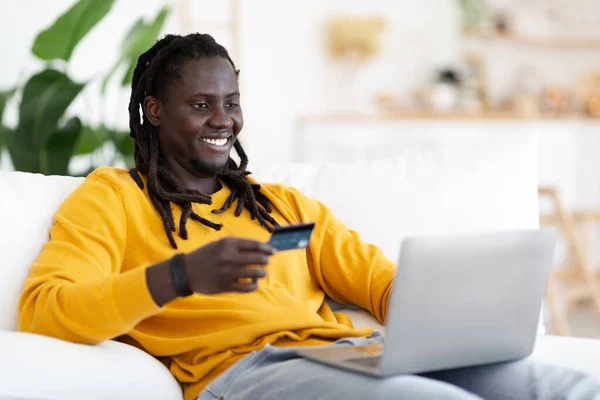 Sonriente Joven Negro Hombre Haciendo Pagos Línea Con Ordenador Portátil —  Fotos de Stock