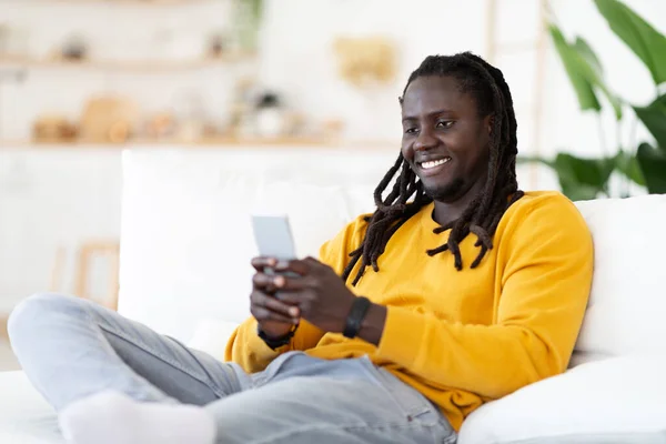 Bonita Aplicación Sonriendo Chico Afroamericano Relajarse Silla Con Teléfono Inteligente —  Fotos de Stock