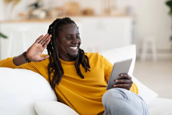 遠隔通信 自宅でビデオ通話のためのデジタルタブレットを使用して笑顔黒人男性 友人や家族とテレビを持っている幸せな若いアフリカ系アメリカ人の男 Webカメラで手を振って — ストック写真