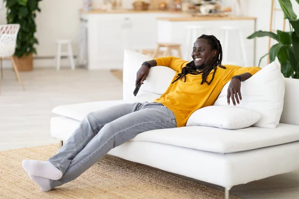 Retrato Joven Negro Sonriente Descansando Sofá Con Mando Distancia Mano — Foto de Stock