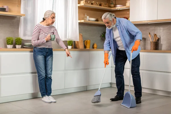 自宅のキッチンで夫を掃除させるシニア女 床にほこりを指摘する潮吹き要求妻 バスルームを利用した高齢夫婦 家事を分担する高齢夫婦 フリースペース — ストック写真