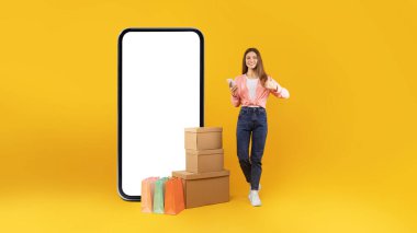 Mobil Alışveriş Teklifi. Big Smartphone 'un yanında, boş ekranda el hareketleriyle alışveriş torbalarıyla satış pozu veren ve paket kutularını sarı arka planda bırakan kadın alıcı. Panorama