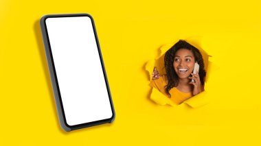 Telefonla konuşan heyecanlı Afrikalı Amerikalı kadın boş cep telefonu reklamları yapıyor ya da yırtık sarı kağıtta delik pozu veriyor. Panorama