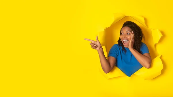兴奋的非洲裔美国女性在空旷的空间广告旁边指尖的手指哇提供在洞中扔黄纸片 工作室背景 看那里概念 — 图库照片