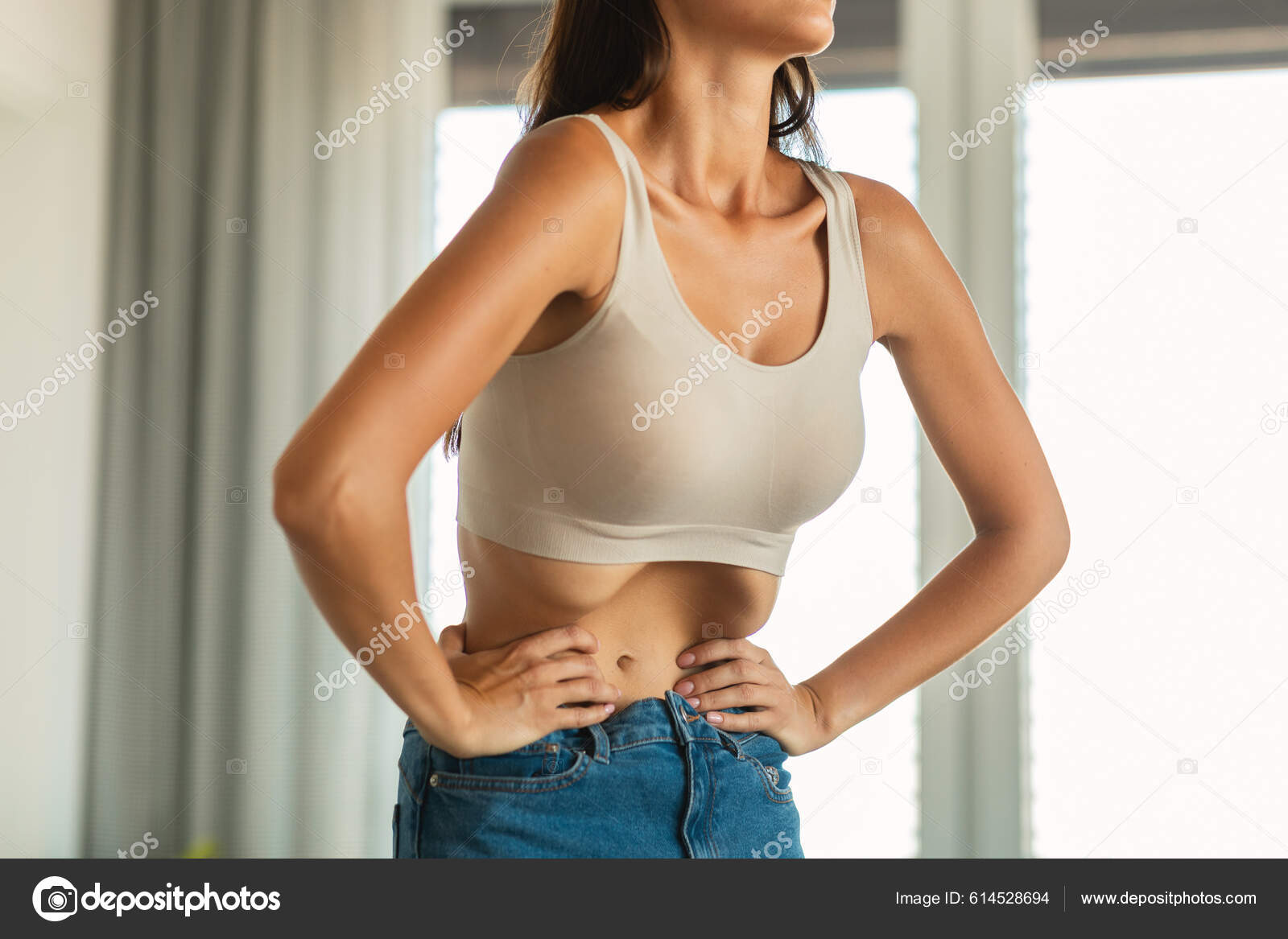 Cropped shot of a young slim woman with toned stomach demonstrating her abs  isolated on a white background. Result of fitness, diet, healthy lifestyle.  Female belly after a workout Stock Photo