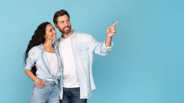 Harika bir reklam ve teklif. Sakallı, Arap kadını kucaklayan ve mavi arka planda, stüdyoda izole edilmiş boş bir yeri işaret eden bin yıllık beyaz adam. Aşk ve aile ilişkisi, online satış.