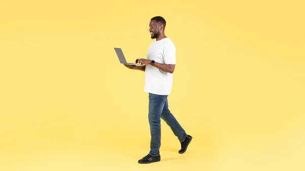 非洲裔美国人使用笔记本电脑在网上行走 通过黄色工作室的背景 互联网技术和自由职业 全长镜头 — 图库照片